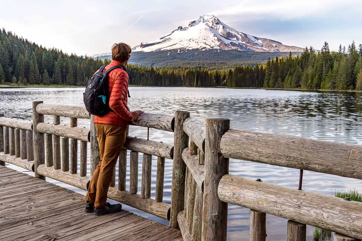 Michael stands on a rustic wooden boardwalk. He is looking out at a lake with a view of Mt. Hood in the distance.