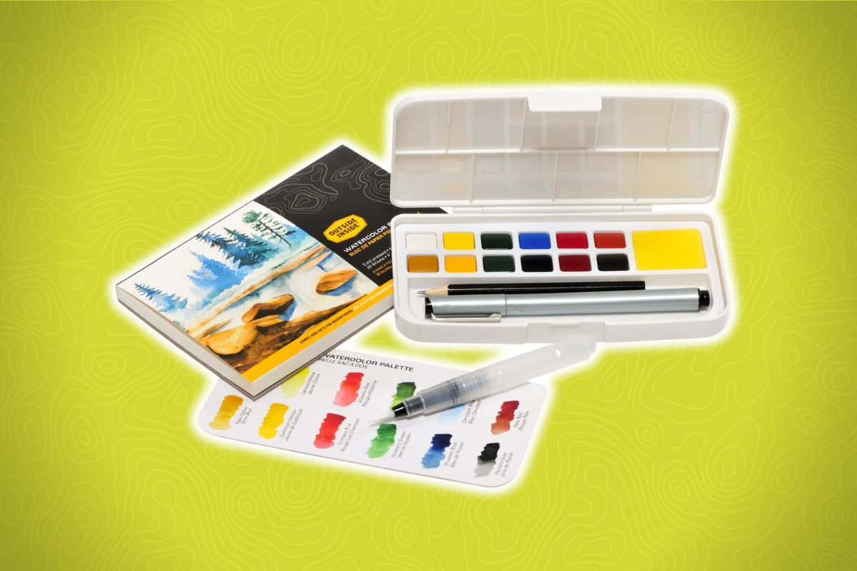 A compact kit with a paint palette, brush pen, and small pad showing a landscape, all set on a yellow background.