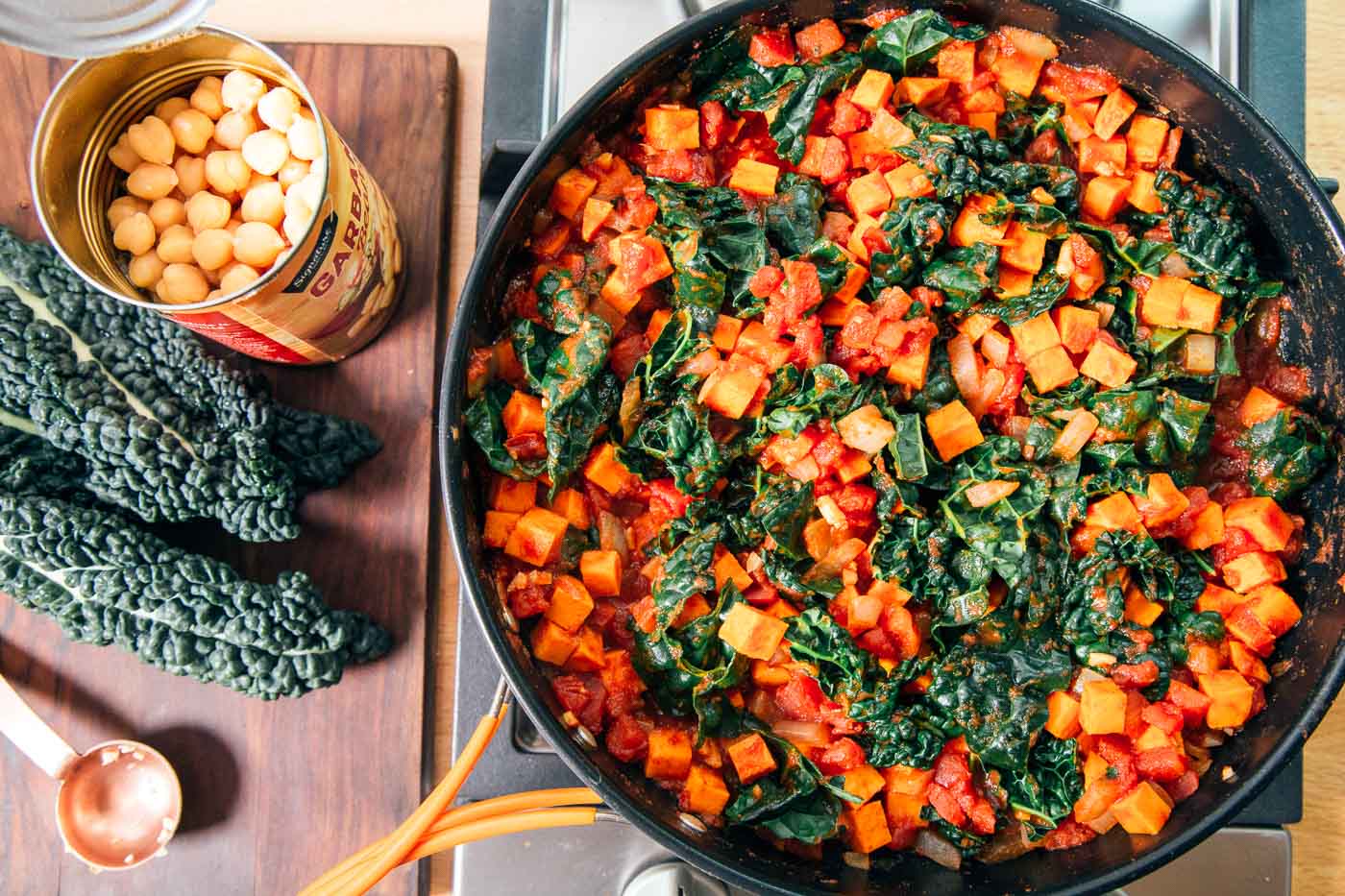 Kale, chickpeas, and tomatoes cooking in a skillet
