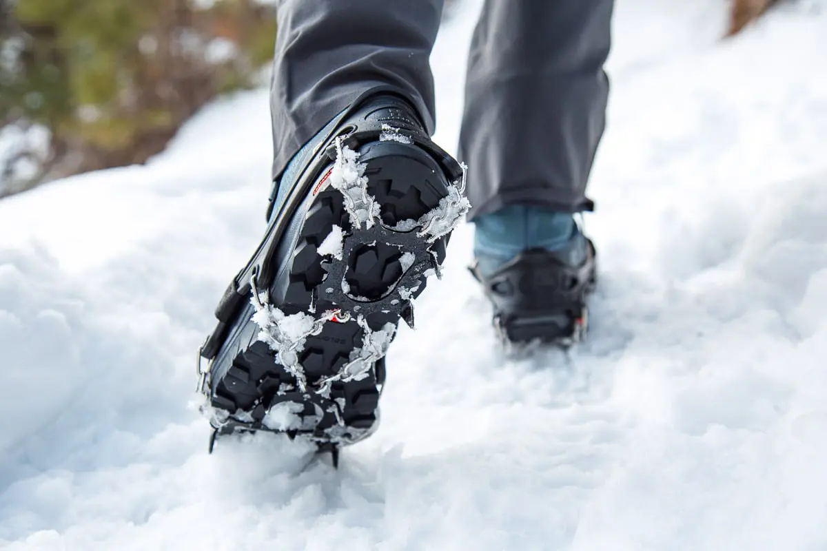 Megan walking with trail crampons attached to a pair of winter hiking boots.