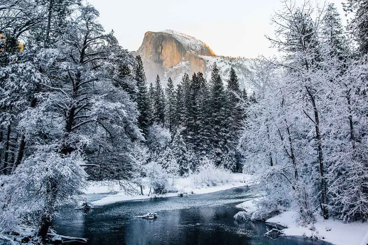 Half Dome covered in snow as seen over the Merced River in Yosemite Valley
