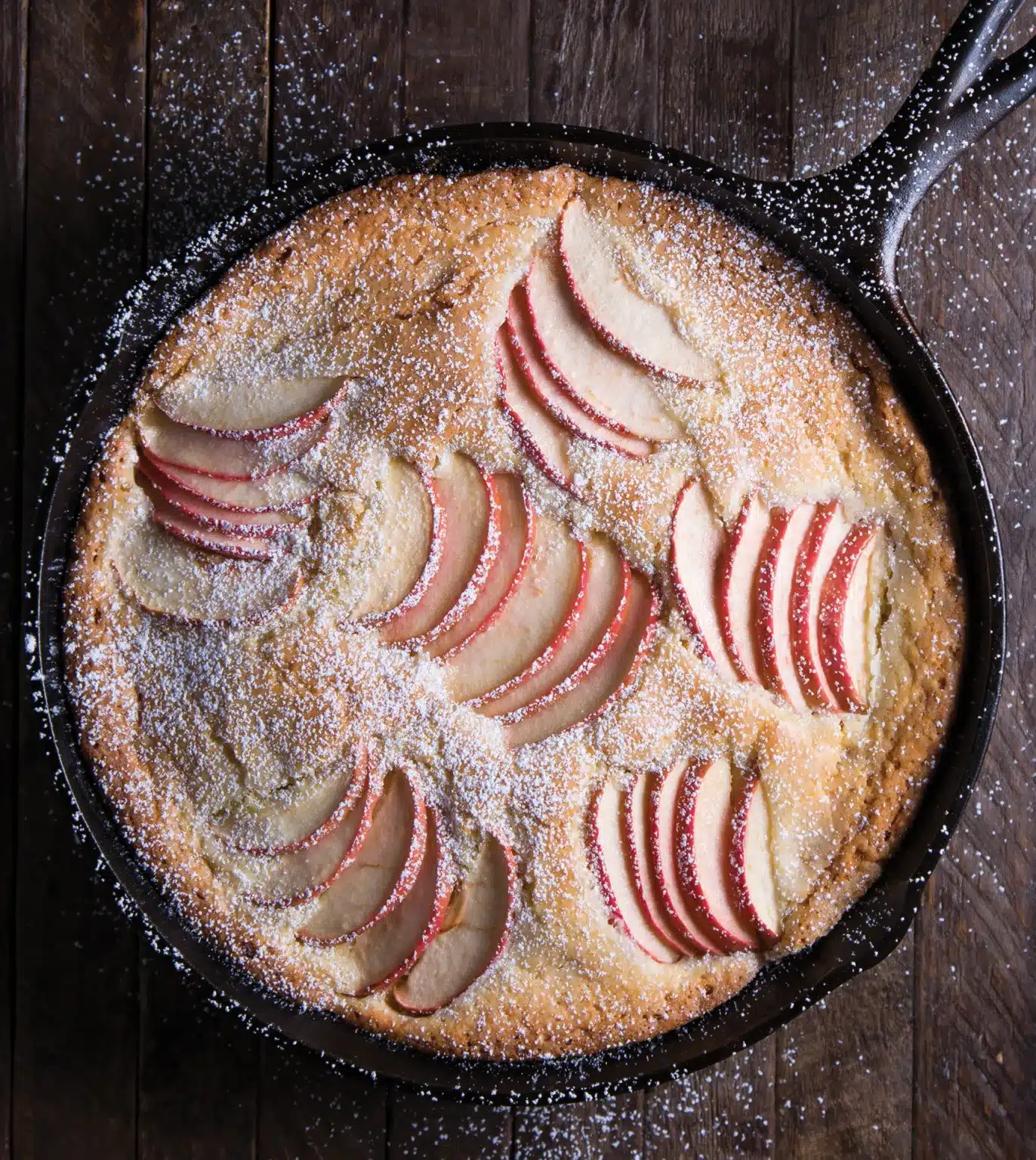 Cake in a cast iron skillet with apple slices.