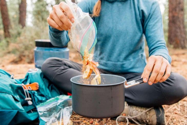 Woman pouring apples into a backpacking pot