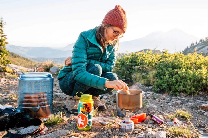 Woman cooking a meal on a backpacking stove.