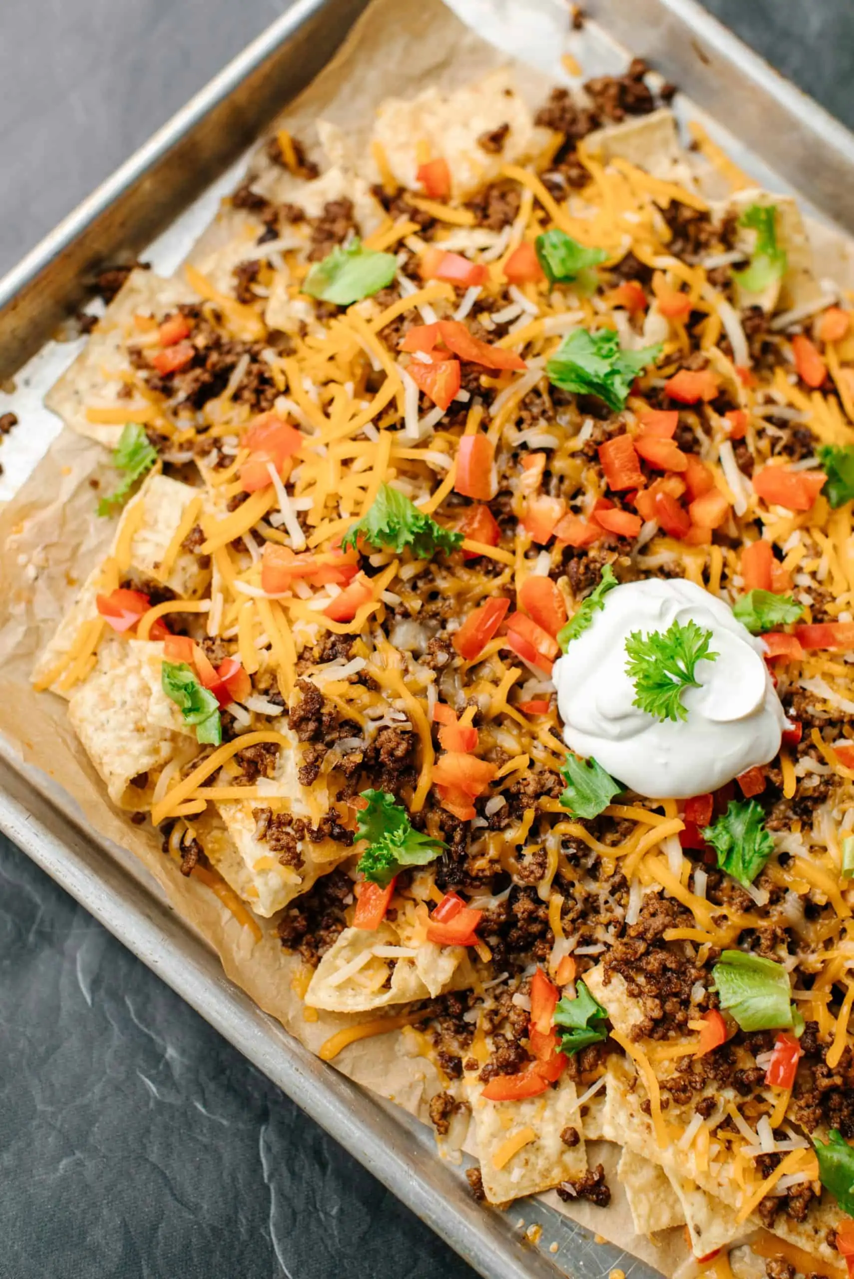 Loaded nachos with cheese, salsa, and sour cream on top of tortilla chips.