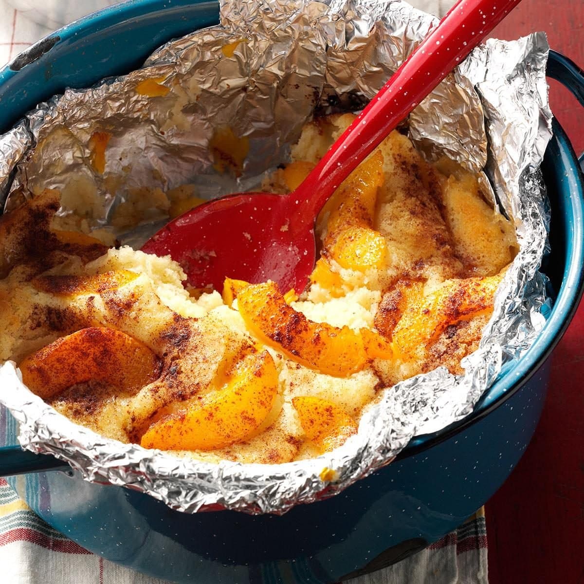 Peach cobbler cooked in a foil packet set in a bowl.