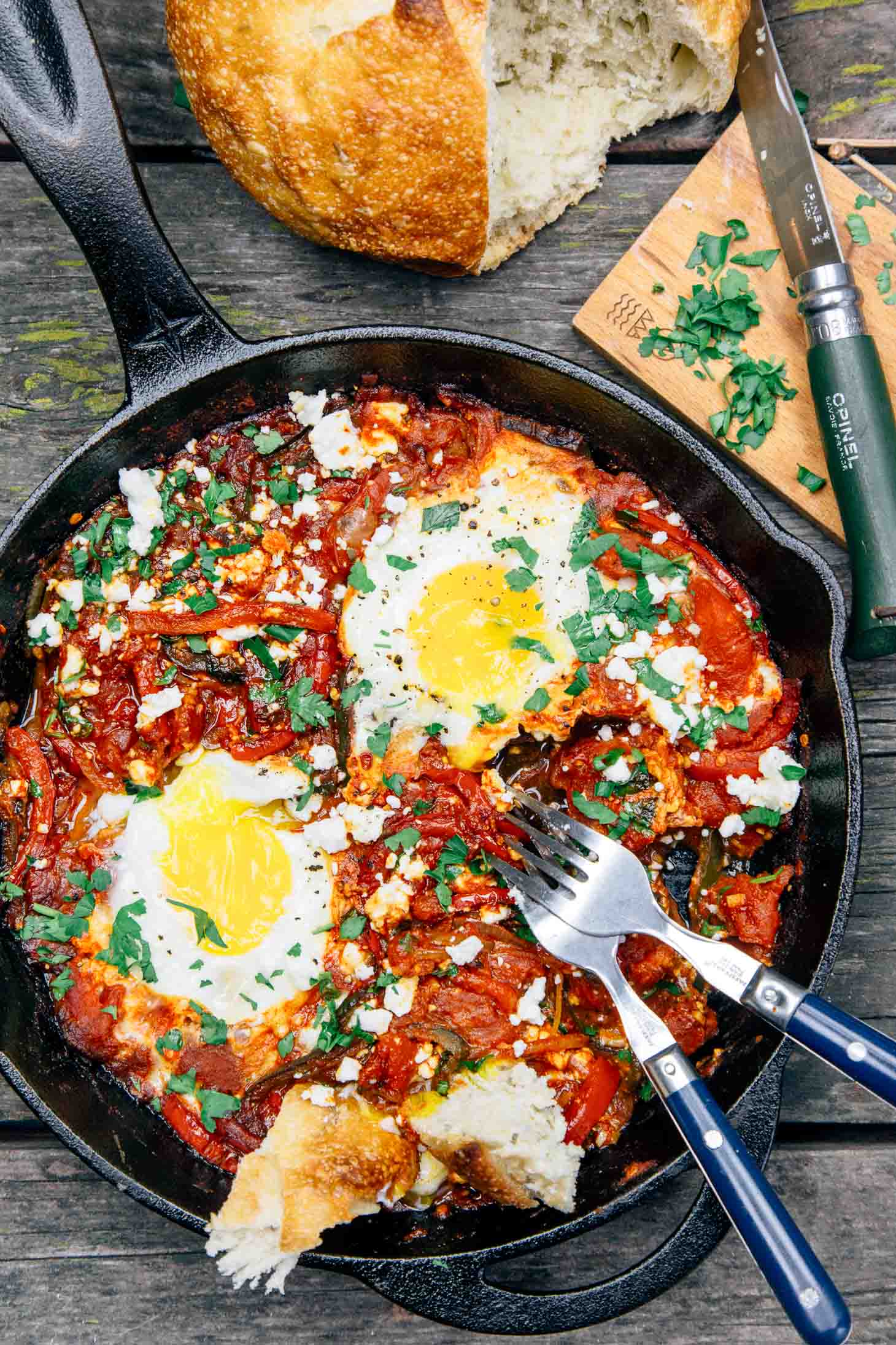 Shakshuka in a cast iron skillet with two eggs and bread