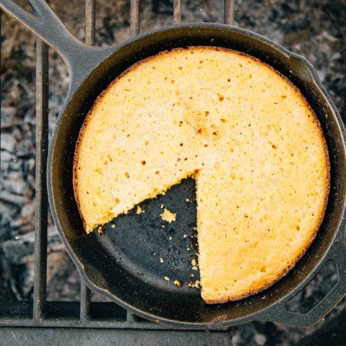 Cornbread with a slice taken out in a cast iron skillet