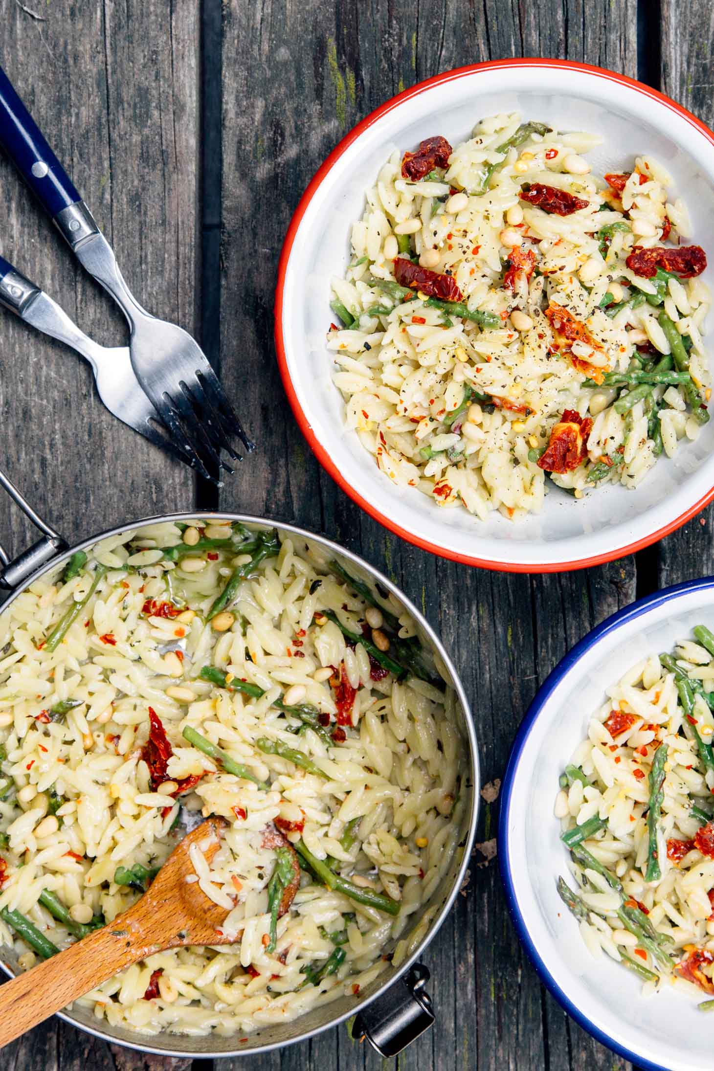 Overhead view of asparagus orzo in a camping bowl on a picnic table