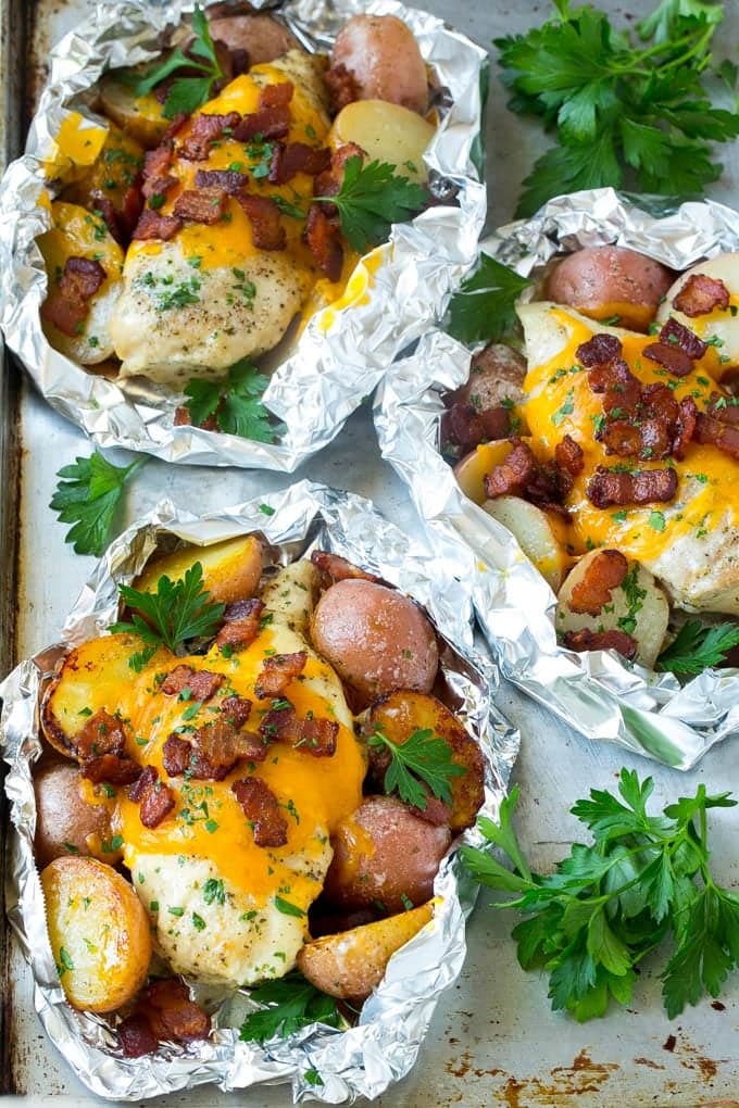 Chicken topped with cheese and potatoes in three foil packets.