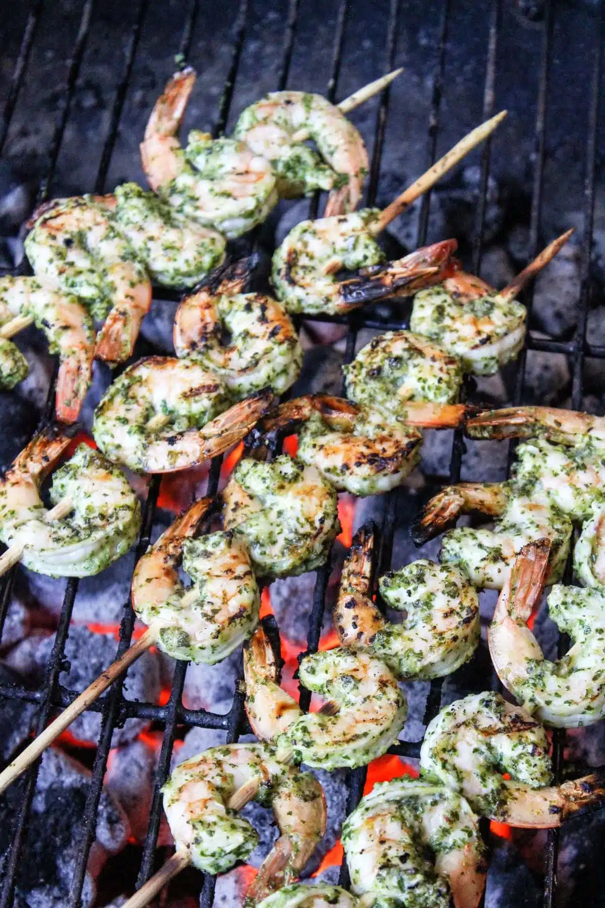 Grilled shrimp skewers with herb seasoning cooking over a charcoal grill.