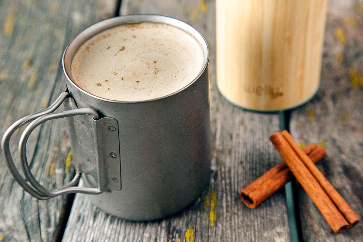 Cinnamon Coconut Latte in a camping mug on a wooden table.