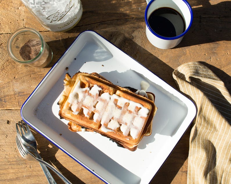 Waffles made from cinnamon rolls with icing in a serving dish.