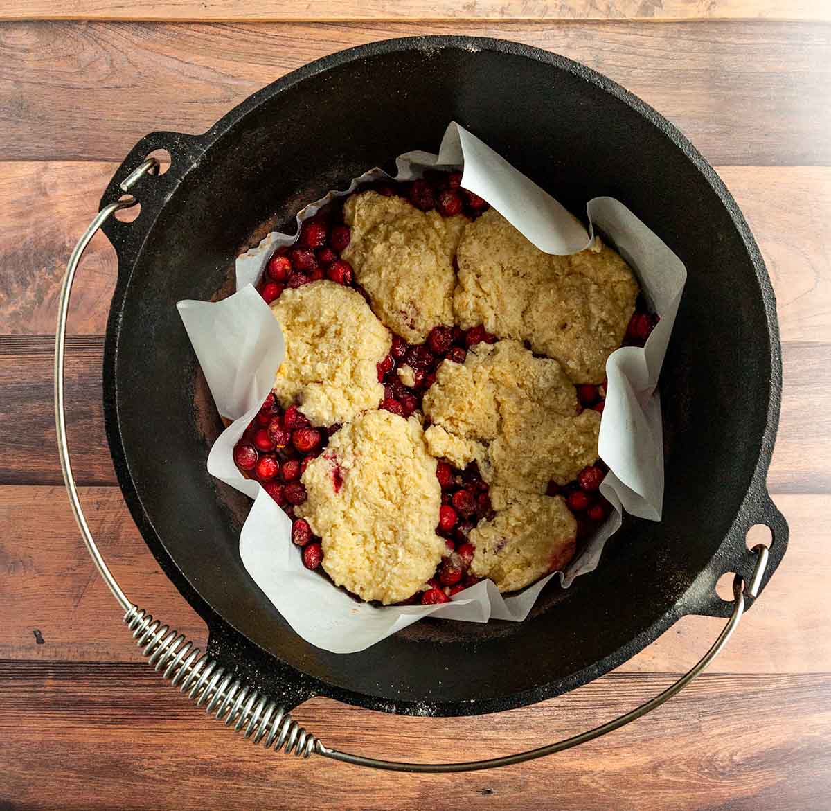 Cranberry cobbler in a dutch oven lined with parchment paper.