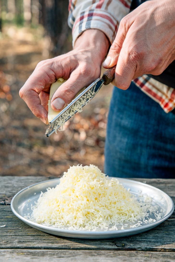 Michael grating cheese over a silver camping plate