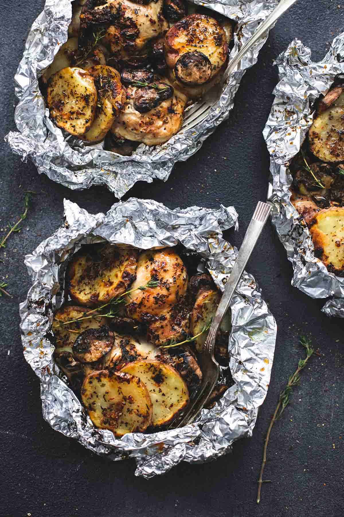 Three foil packets filled with chicken and potatoes.