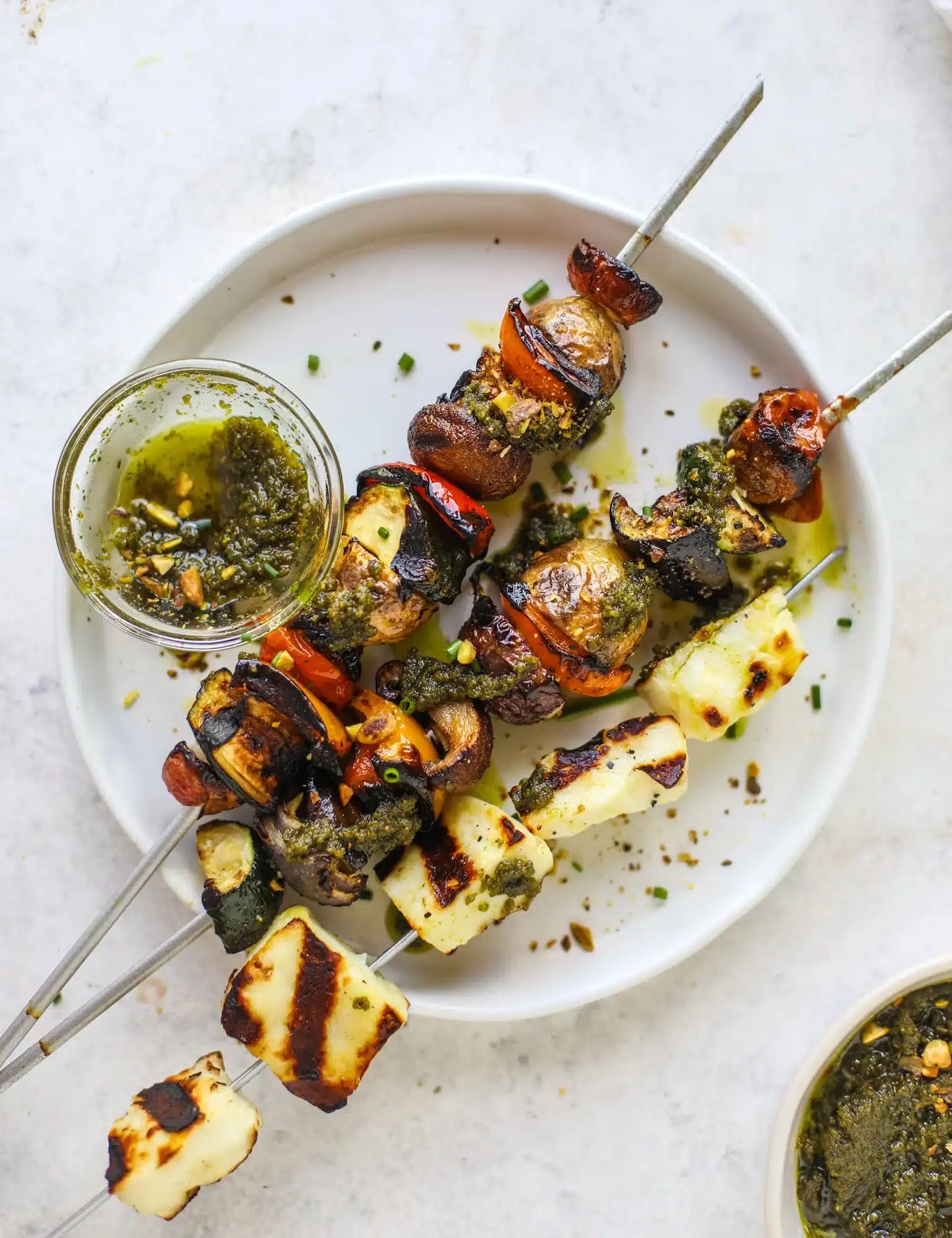 Grilled vegetable and halloumi cheese skewers served with a side of herb sauce.
