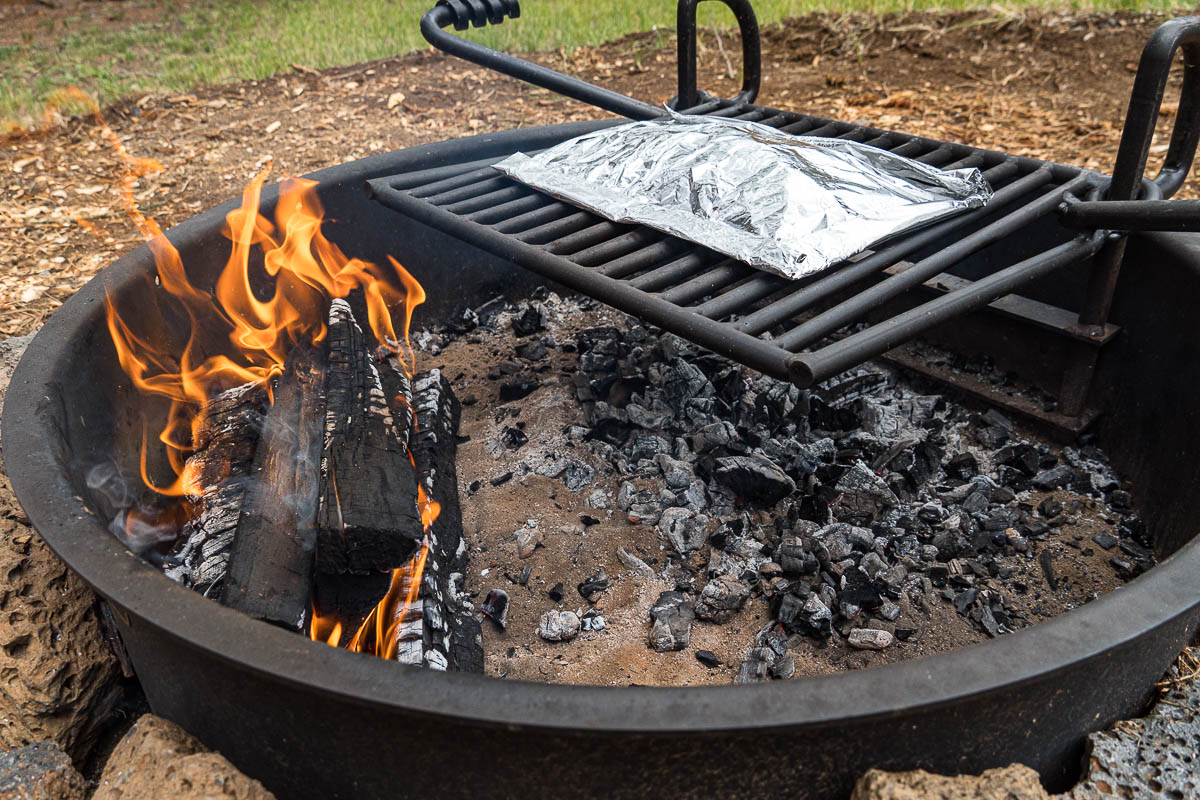 Foil packet on a campfire grill over a bed of embers