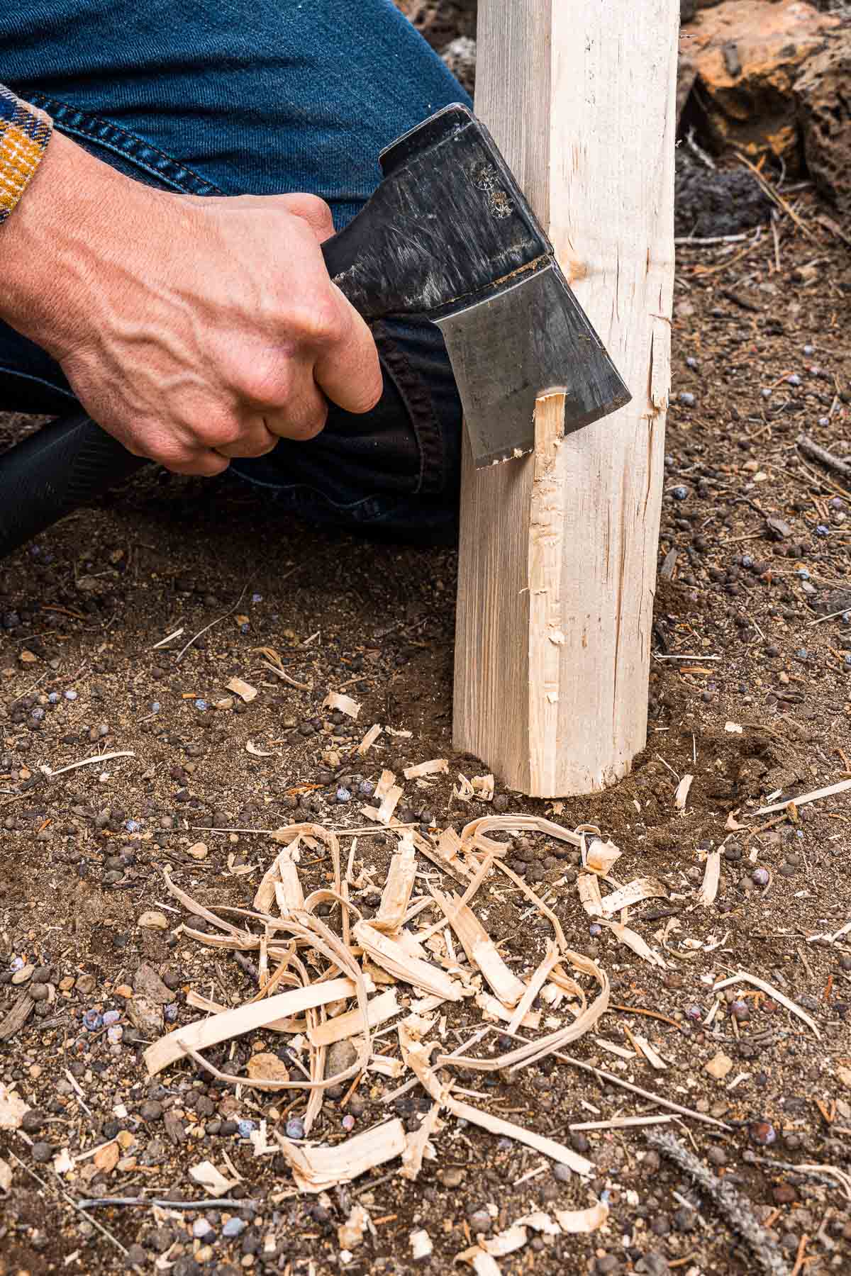 Michael using a hatchet to create tinder from a small log