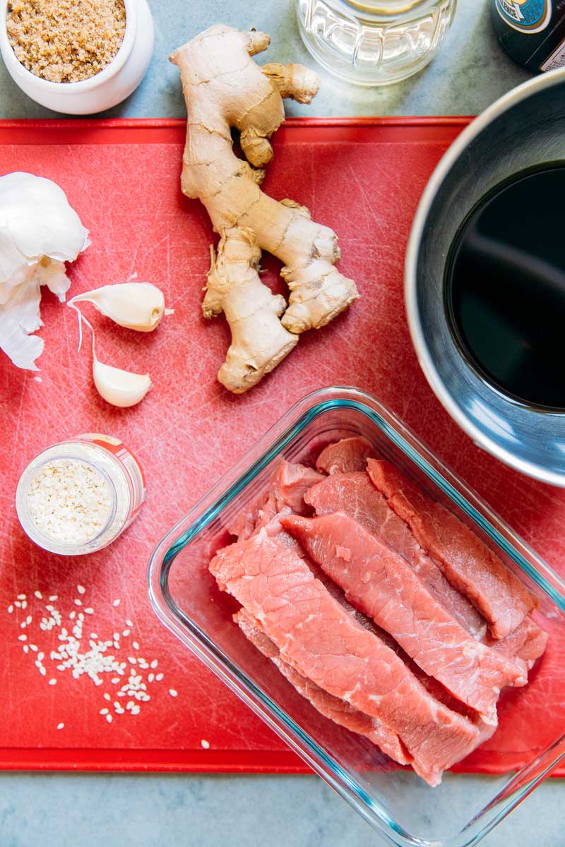 Overhead view of beef jerky marinade ingredients including ginger, garlic, soy sauce, and sesame seeds.