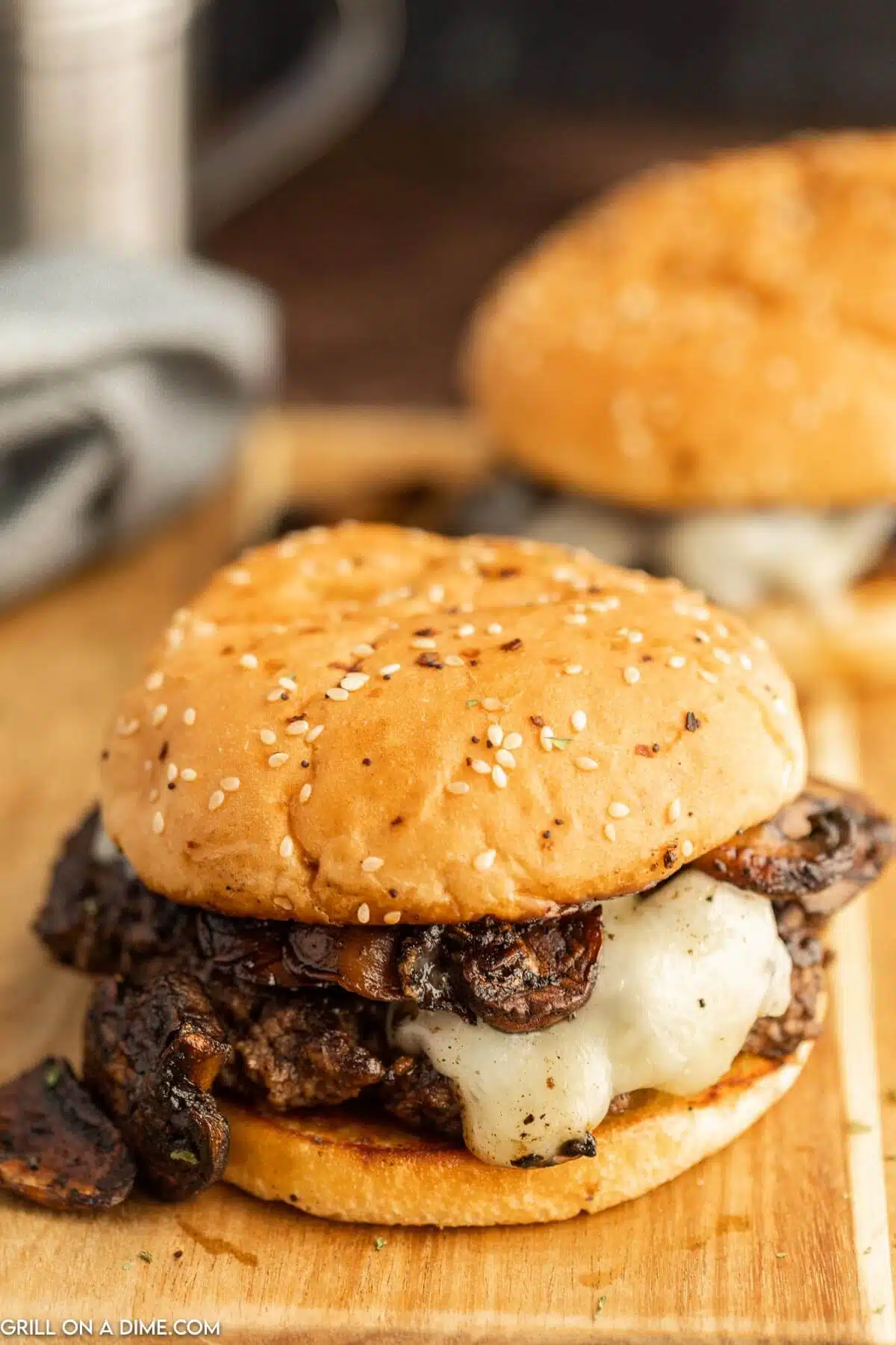 Mushroom burger with melty swiss cheese on a wood surface.