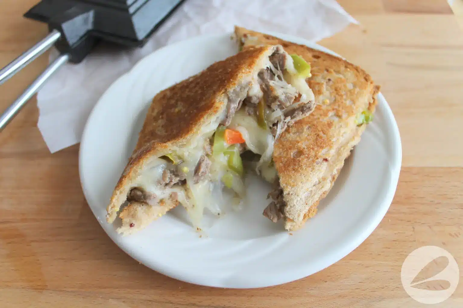 Steak, vegetables, and melted cheese inside grilled bread.