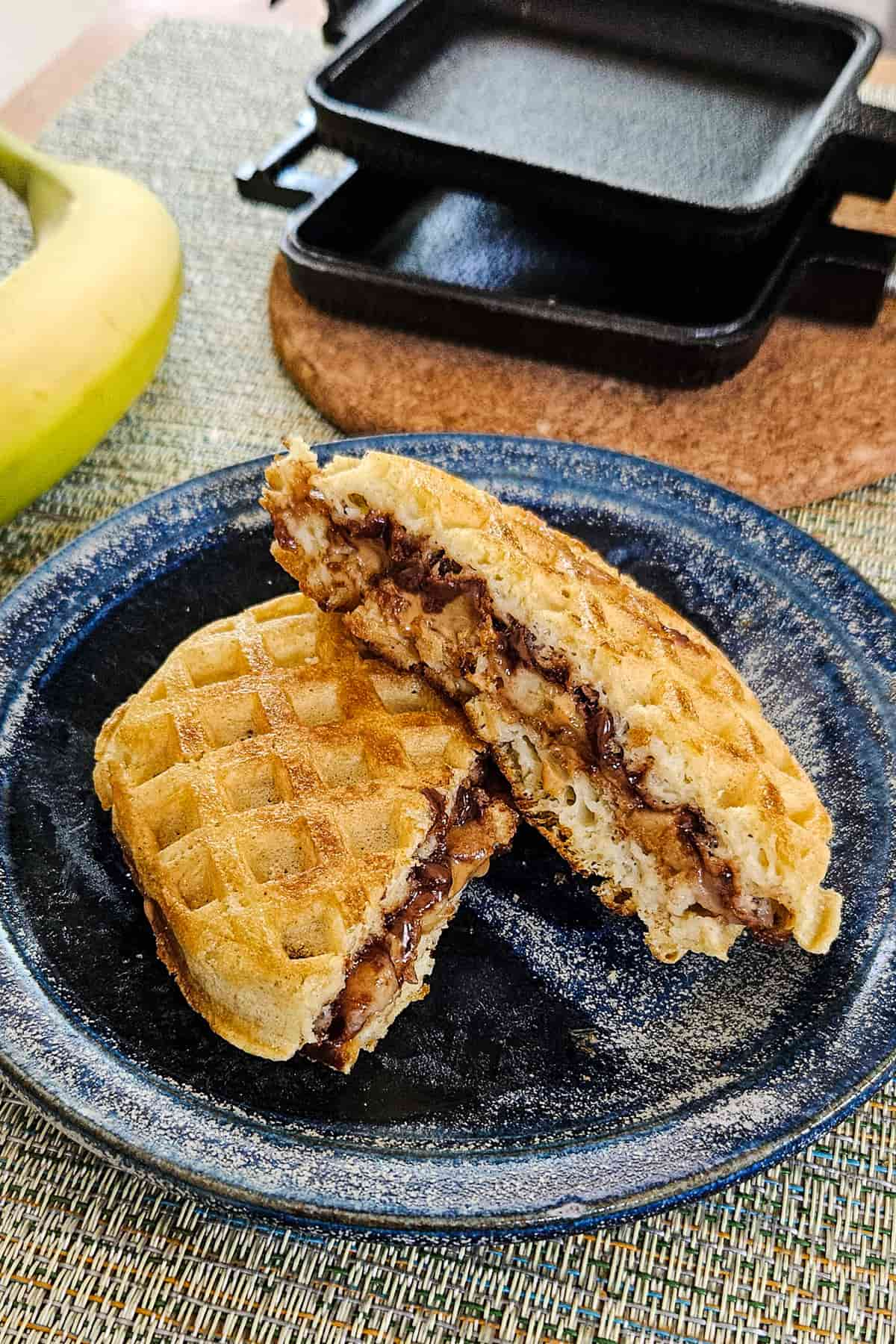 Waffles made in a pie iron on a blue camping plate.