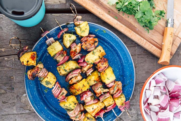 Pineapple chicken kabobs on a blue camping plate