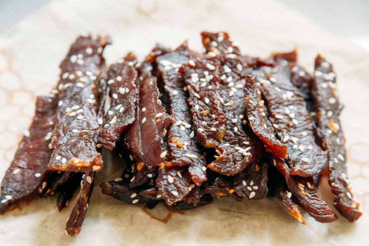 Side view of teriyaki beef jerky stacked on a napkin.