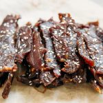 A pile of beef jerky with sesame seeds