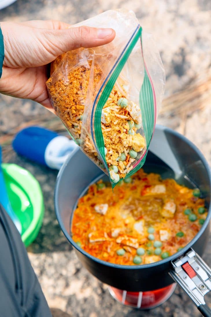 Pouring the ingredients for red curry rice into a backpacking cookpot